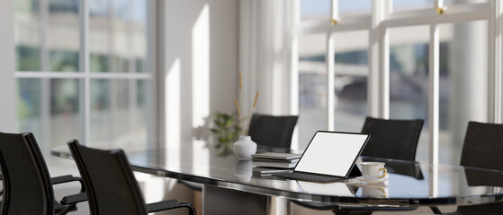 A white-screen digital tablet mockup on a meeting table in a modern meeting room. place of work
