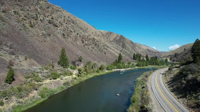 Snake River Idaho with two lane road on river bank and car driving by- aerial
