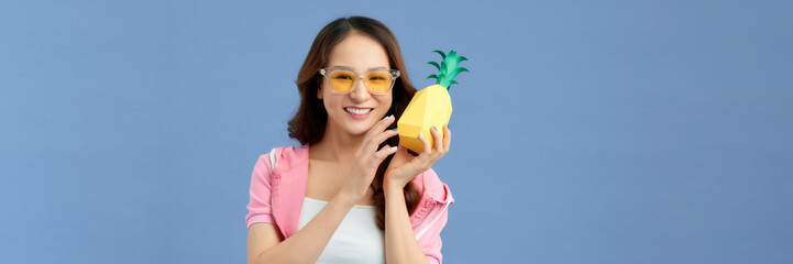 Beautiful young asian woman holding pineapple and smiling