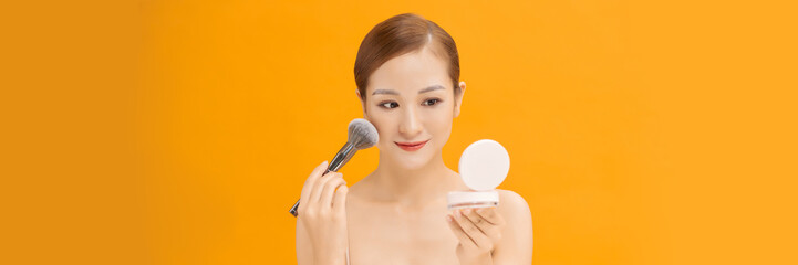 Young woman applies powder on the face using makeup brush. web banner.
