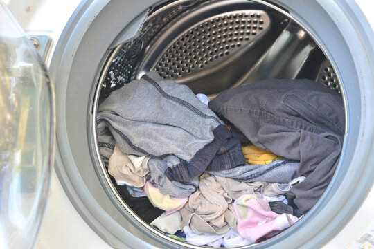 Open door of washing machine with laundry inside.