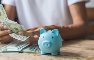 Piggy bank with money and business man work at wooden table,saving money concept,selective focus.