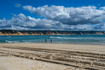 Fishing at Double Island Point, Rainbow Beach, Queensland, Australia. Man and boy fishing with Rainbow coloured sands in the background.