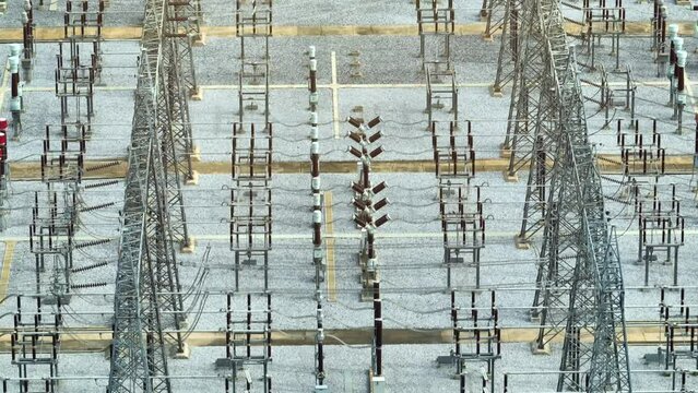 A drone reveals the high voltage power station as a high-tech oasis, where electricity flows relentlessly through the veins of steel towers, creating a geometric pattern against the earth's canvas.

