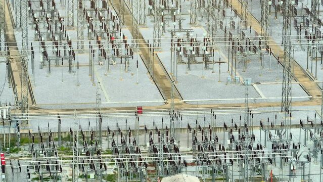 A high voltage power station, a silent sentinel of energy, stands tall, channeling the lightning's grace into the veins of our cities, illuminating our world with a powerful embrace. Aerial view.
