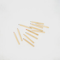 flatlay photo of messy wooden colored pencils on white background