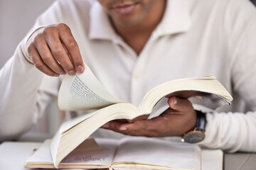 Hands, man and bible study at desk, home and reading for faith, knowledge and spiritual guide....