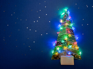 decorative christmas tree with glowing holiday lights on blue background.