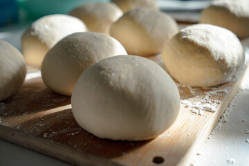 close ups of homemade pizza and pretzel dough on a cutting board with flour 
