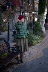 A woman in fall clothes near a bench in the park.