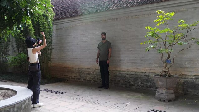 Photoshoot in garden location. Girl photographer supervising male model