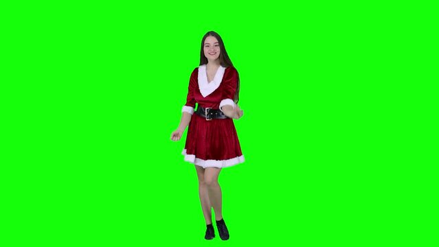 Happy and smiling Caucasian female dancer dancing in front of the green screen in Santa Christmas holiday outfit cosplay