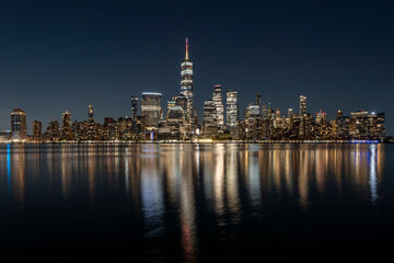 New York City's Manhattan skyline at night, photographed from Jersey City with Hudson River in...