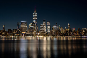 Manhattan Skyline at night with beautiful reflection in the hudson river in the front - obrazy, fototapety, plakaty