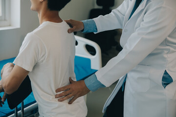 Doctor or physical therapist examines back pain and spinal area to give advice within the...