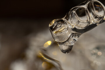 A drop of cosmetic aromatic oil drips from the pipette. Front view.