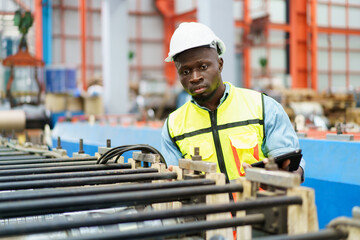 American - African worker inspecting machine in factory, machanical engineer working on machines in...