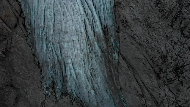 Aerial view of the Gauli glacier in the Bernese Oberland region of the Swiss Alps with a panning view from the glacial tongue up towards the mountain peaks.