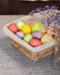 Fototapeta na wymiar Basket with colored eggs and bouquet close-up