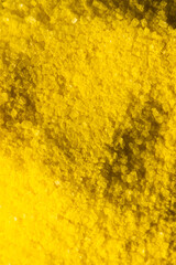 Vertical image of close up of yellow powder with copy space background