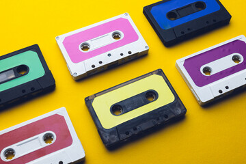 Close up of six colourful cassette tapes arranged on yellow background