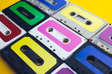 Close up of nine colourful cassette tapes arranged on yellow background