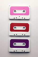 Overhead view of three colourful cassette tapes arranged on white background