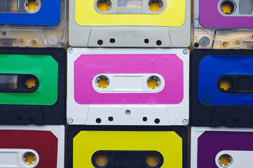 Overhead view of nine colourful cassette tapes arranged on yellow background