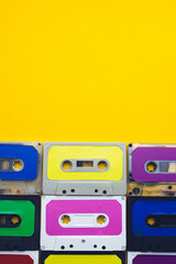 Overhead view of nine colourful cassette tapes with copy space on yellow background
