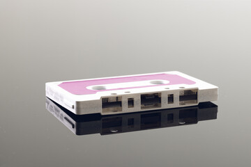 Close up of white and pink cassette tape on grey background