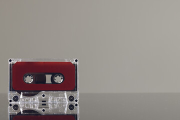 Close up of red cassette tape on grey background with reflection