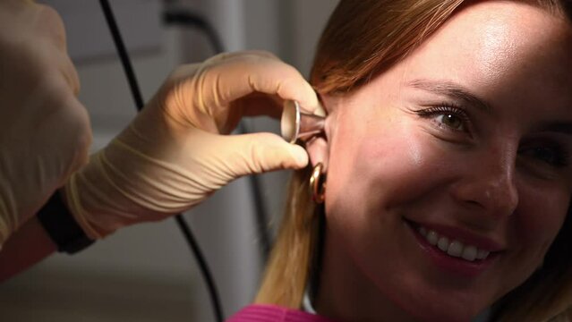 otolaryngologist conducts medical examination of ear with otoscope closeup