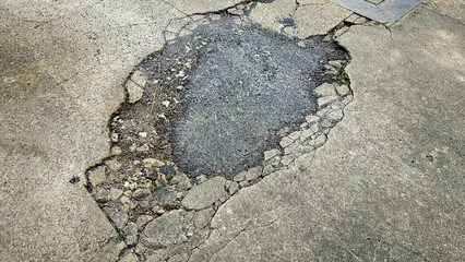 A picture of potholes at damage road, Damaged asphalt pavement road with potholes. Potholes on a road. Damaged road with potholes caused. Hole in the asphalt caused by deterioration of the pavement.