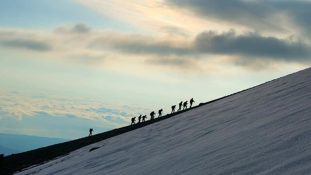 The struggle of the crowded group of climbers and the harmonious team walking on the snow at the top
