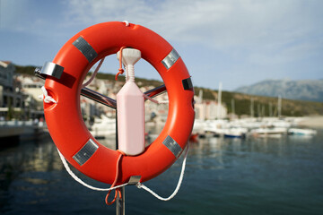Lifebuoy on a rack with a lock at the pier against the backdrop of mountains
