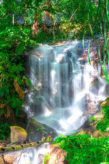 beautiful cascading waterfall over rocks long exposure in Chiangmai Chiang mai mountains northern thailand amongst lush green tropical rainforest