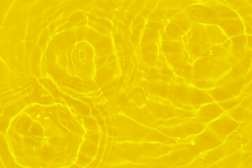 Yellow water with ripples on the surface. Defocus blurred transparent gold colored clear calm water...