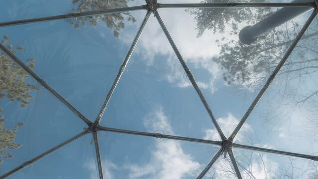 A timelapse of a view from the inside of a geodesic dome accommodation airbnb during a beautiful spring sunny day located in the middle of the forest shot in 4k.