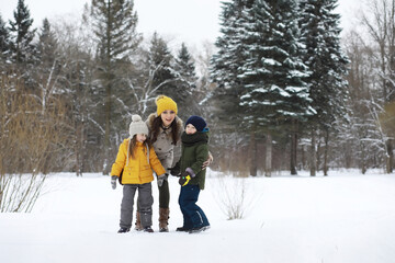 Happy family playing and laughing in winter outdoors in the snow. City park winter day.