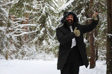 Outdoor portrait of handsome man in coat and scurf. Bearded man in the winter woods.