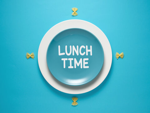 The message Lunch Time written on a blue plate designed as a clock. Lunch break concept.