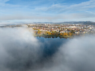 Luftbild von der Stadt Radolfzell am Bodensee mit herbstlicher Vegetation und ziehenden Nebelschwaden über dem See