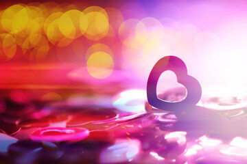 Abstract colored background. Red toy in the shape of a heart on a glitter and bokeh background.