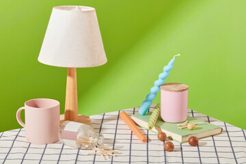 Scented candles and colored candles are displayed on the table with props. Checkered tablecloth with green background. Candles are commonly used for many uses such as lighting, decoration, etc.