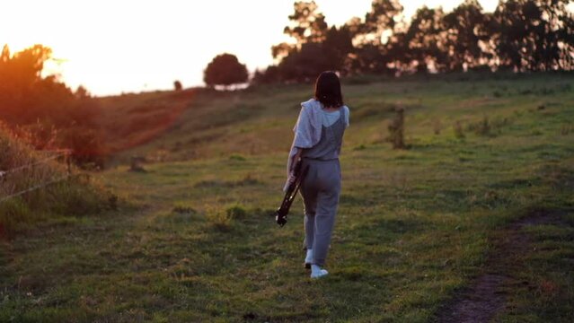 Sunset Stroll: Young Woman Walking Alone in Countryside at Dusk