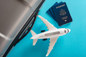 Miniature toy airplane with US passport and suitcases isolated on blue background