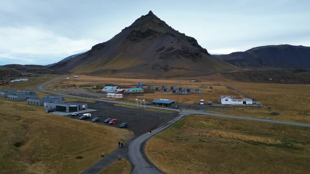 Small town in an Icelandic glacial alluvial plain, a vast expanse and a large mountain in the center. Skeidararsandur, aerial drone shot. 