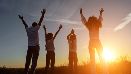 Happy family raise hands up overlooking setting sun. Concept of movement and harmony in relation to...
