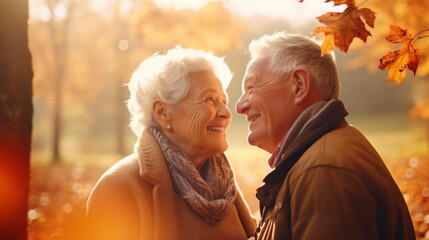 秋冬の自然の中で、高齢者の老夫婦2人が笑顔で向かい合って笑って微笑んでいる写真 - obrazy, fototapety, plakaty