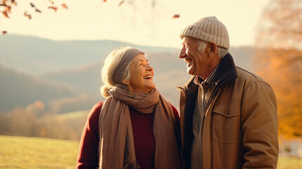秋冬の自然の中で、高齢者の老夫婦2人が笑顔で向かい合って笑って散歩している写真 - obrazy, fototapety, plakaty